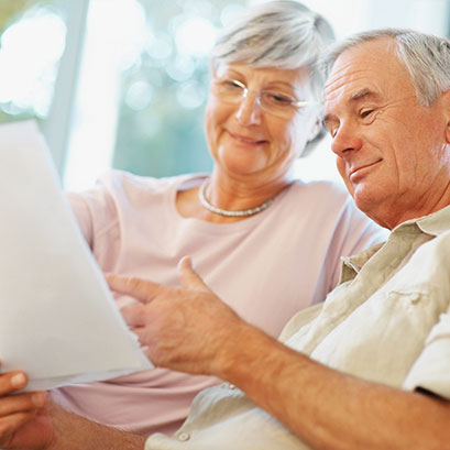 Photo of a couple looking at documents. Links to Gifts of Life Insurance